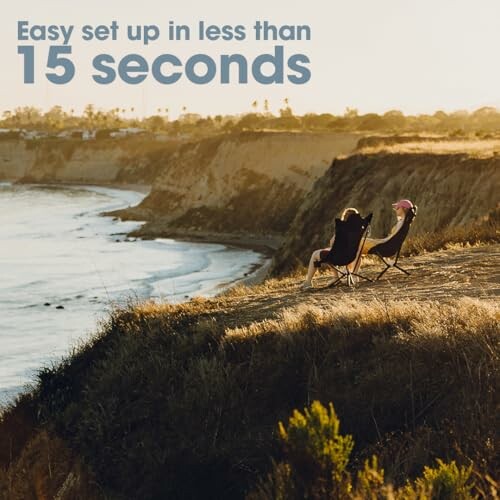 Two people sitting on camping chairs by a cliffside overlooking the ocean at sunset