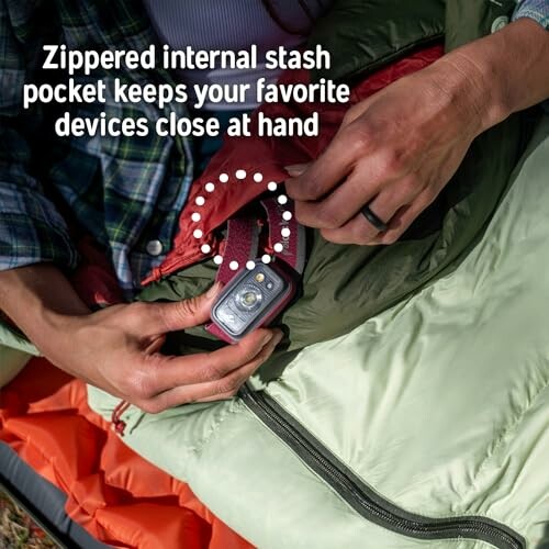 Person using zippered internal stash pocket in a sleeping bag.